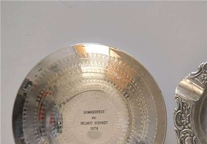 Silberfarbener Aschenbecher mit zwei Putten als Motiv, sowie eine silberne Schale. privat