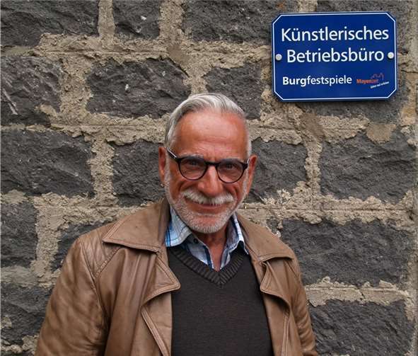 So kennt man ihn – ein verschmitztes Lächeln im Gesicht und die Welt fest im Blick: Mayens scheidender Intendant Peter Nüesch vor dem Büro der Festspiele.  Schürer