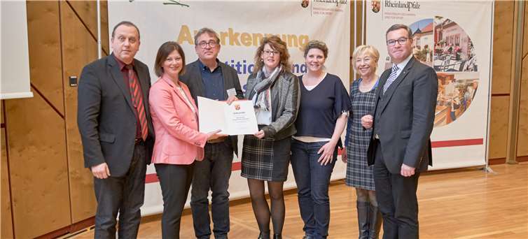 Staatssekretärin Nicole Steingaß (2.v.li.) überreicht die offizielle Anerkennung des Ortsteils Burgbrohl-Oberlützingen als Schwerpunktgemeinde der Dorferneuerung an den Beigeordneten Udo Rindsfüsser (3.v.li.) und an die Beigeordnete Simone Schneider (4.v.li.). Bei der feierlichen Übergabe in Budenheim waren Bürgermeister Johannes Bell (li.), Kreisbeigeordneter Horst Gies, Planerin Eva Steinberger-Theisen und Bauamtsmitarbeiterin Angelika Görres (v.re.) mit dabei.Foto: MdI RLP