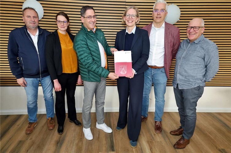 Staatssekretärin Simone Schneider (Mitte) überreicht einen Förderbescheid in Höhe von 1.760.000 Euro für die Ortskernentwicklung an Altenahrs Ortsbürgermeister Dr. Neofitos Arathymos. Über die Mittel aus dem Bund-Länder-Programm „Wachstum und nachhaltige Entwicklung – Nachhaltige Stadt“ freuen sich auch Dominik Gieler (2. v. re.), Bürgermeister der Verbandsgemeinde Altenahr, Frank Heuser (re.), Leiter der Bauabteilung der VG Altenahr (re.), Nadine Hamacher (2. v. li.) aus der Bauabteilung sowie Frank Müller (li.), Beigeordneter der Ortsgemeinde Altenahr.  Foto: Thorsten Trütgen / VG Altenahr