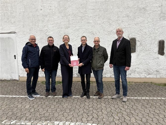 Staatssekretärin Simone Schneider übergibt den Förderbescheid an die Ortsgemeinde Niederdürenbach. V.l.n.r.: Büroleiter Armin Seiwert, Beigeordneter Marco Mather, Staatssekretärin Simone Schneider, Ortsbürgermeister Sebastian Schmitt, 1. Beigeordneter Raymund Bley, 1. Beigeordneter der Verbandsgemeinde Brohltal Rolf Hans.  Foto: Florian Herrmann, Verbandsgemeindeverwaltung Brohltal