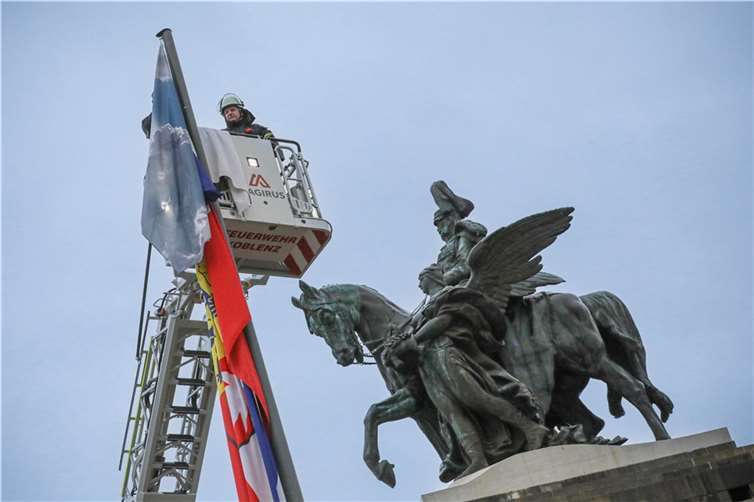 Statt Landesflaggen wehen nun bis Montag 16 Horizonte aus den 16 Bundesländern am Deutschen Eck. Die Feuerwehr Koblenz hat am Donnerstagmorgen unter den Augen des Kaisers das Werk „ONE SKY FLAGS – Horizonte der Freiheit, 16 Bundesländer – 16 Himmelsbilder“ der Künstlerin Yvonne Lee-Schultz montiert.  Fotos: Stadt Koblenz/Andreas Egenolf