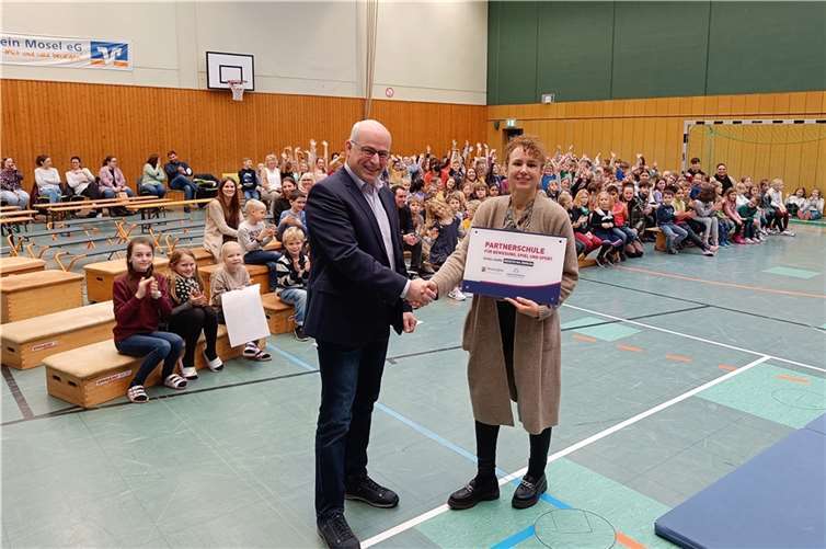 Stefan Kölsch von der ADD überreicht Rektorin Petra Spies das Zertifikat in Form eines Schildes. Sie und das gesamte Kollegium können zurecht stolz sein, da die Grundschule Kruft erst die 14. Grundschule in Rheinland-Pfalz ist, die diese Auszeichnung bisher erhalten hat. Foto: VG Pellenz