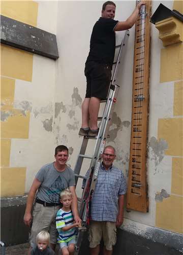 Stefan Pantenburg, Paul Radermacher (unten) und Lukas Radermacher brachten das Barometer an der Fassade der Kirche an. privat