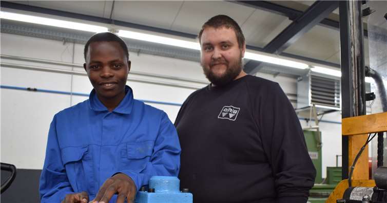 Steffen Linscheid, Ausbildungsbeauftragter bei chg in Nassau, zeigt dem Gast aus Mabira, wie Werkzeuge den richtigen Feinschliff erhalten, während der Elektriker Deocta unter fachkundiger Anleitung von Tim Pfeiffer im Leifheit-Campus Kabel verlegt.Fotos: privat