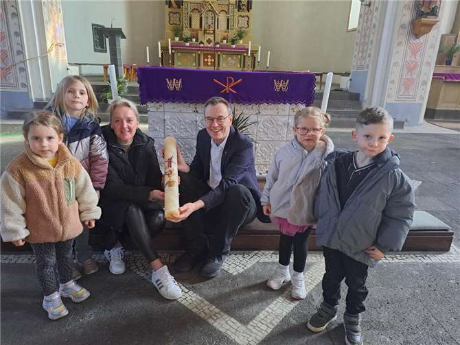 Stellvertretend für alle mitwirkenden jungen Künstler überreichen einige Kinder mit ihrer Erzieherin Sandra Mörsdorf in der Pfarrkirche Sankt Arnulf die neue Osterkerze an Pastor Norbert Missong. Foto: Isabell Fischer