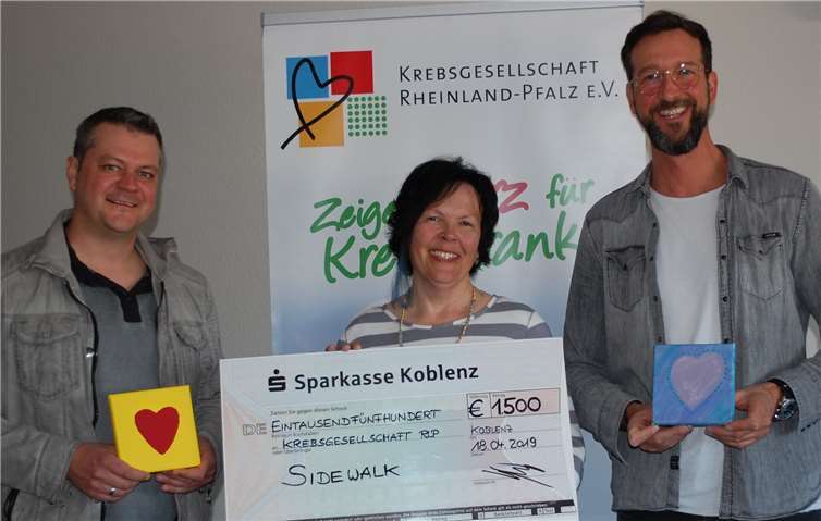 Stellvertretend für die Band „Sidewalk“ überreichten Gitarrist Christoph Winkel (re.) und Keyboarder Christoph Grotejohann das Ergebnis ihrer außergewöhnlichen Spendenaktion in Höhe von 1.500 Euro an Gerti Kunz, Leiterin des Koblenzer Beratungszentrums der Krebsgesellschaft Rheinland-Pfalz. Das Geld kommt der kostenfreien Beratung und Begleitung von Krebspatienten und ihren Familien zugute. Foto: Krebsgesellschaft Rheinland-Pfalz