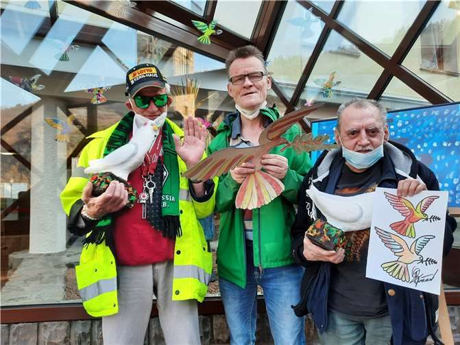 Stellvertretend für die unzähligen Taubenmaler: (v. l.) Helmut Görges, Hubert Lucht und Franz-Josef Dosot präsentieren Friedenstauben auf Papier und aus Pappmaché, die den Haupteingang bevölkern. Foto: Kloster Ebernach