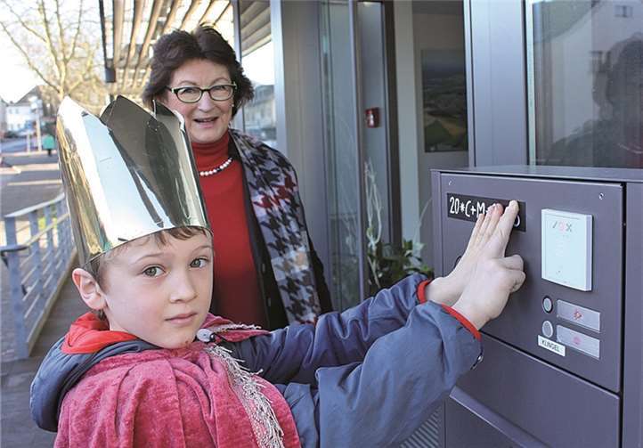 Sternsinger Noah bringt den Segensspruch am Rathaus an.