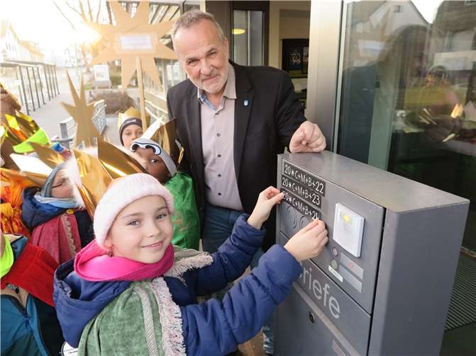 Sternsinger bringen im Beisein von Bürgermeister Jörg Schmidt den Segensspruch 2024 an der Rathaustür an.