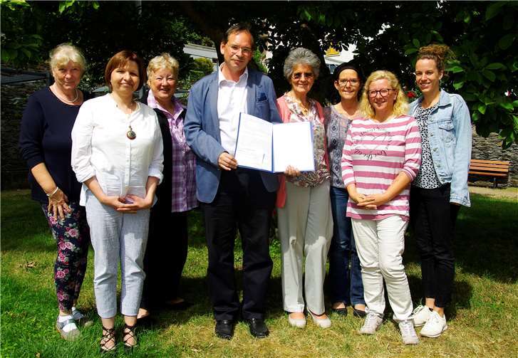 Stiftungs-Geschäftsführer Oliver Roland (Mitte) übergibt die Auszeichnung an Sr. Dr. Lea Ackermann (4.v.r.) im Beisein eines Teils der Belegschaft.Foto: Arno Boes für SOLWODI