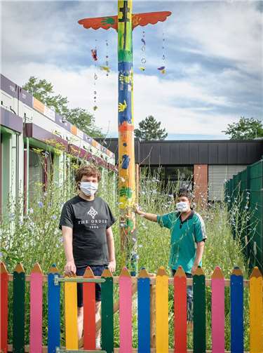 Stolz präsentieren Leon und Florian stellvertretend für die Klassengemeinschaft den Totem-Pfahl auf der blühenden Wiese. Foto: Ingo Görres