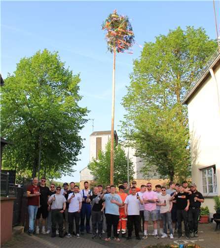 Stolz präsentieren sich die Oberzissener Junggesellen mit ihrem Maibaum, den Ortsbürgermeister Christof Bürger (links) gestiftet hat.  Foto: GS