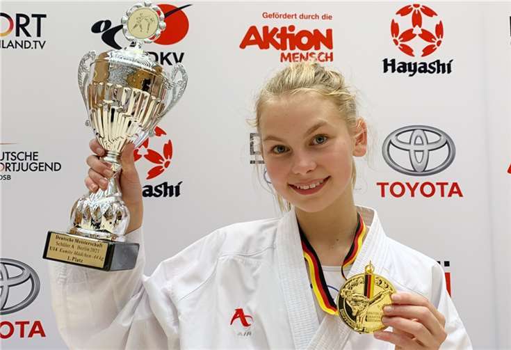 Stolz präsentiert die dreifache Deutsche Karatemeisterin Pokal und Medaille.