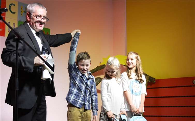 Stolz wirft sich der erstplatzierte Enno in Siegerpose. Gemeinsam mit der zweitplatzierten Maxine und der drittplatzierten Kim, freut er sich über die Gratulation und den Siegerpreis von Landrat Manfred Schnur.