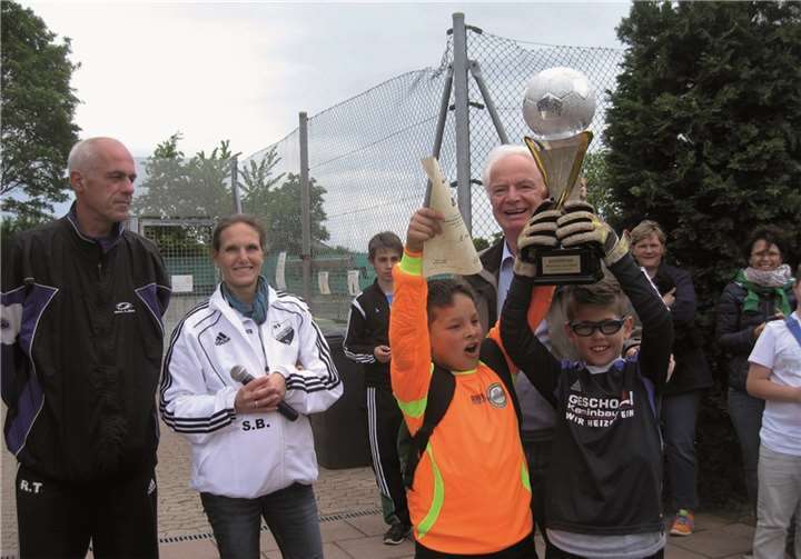 Stolze Sieger: Die Abordnung der Jungen-Mannschaft der KGS Wormersdorf zeigen ihren Mitspielern den Pokal. Präsident Joachim Krüger, Schulleiterin Sandra Bures und Ralf Thomm vom SW Merzbach freuen sich mit ihnen. privat