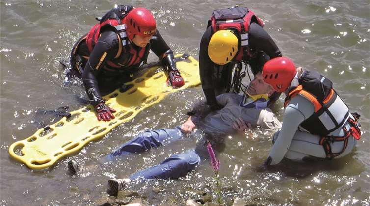 Strömungsretter versorgen einen ins Wasser gestürzten Patienten.