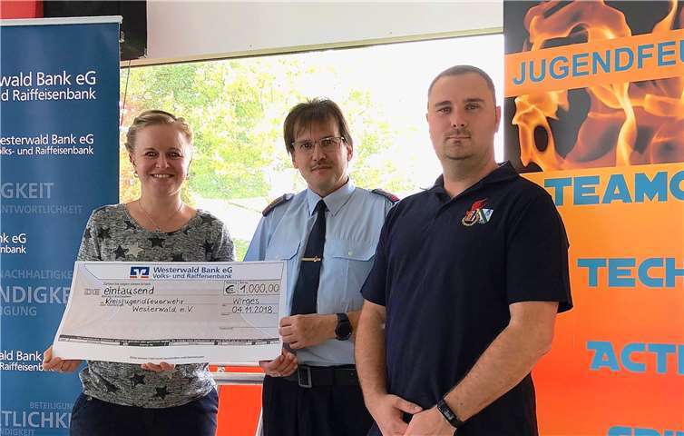 Sylvana Schmidt von der Westerwald Bank in Wirges (li.) übereichte den 1.000-Euro-Scheck an Kreisjugendfeuerwehrwart Thomas Krekel und dessen Stellvertreter Florian Bach (re.). Privat