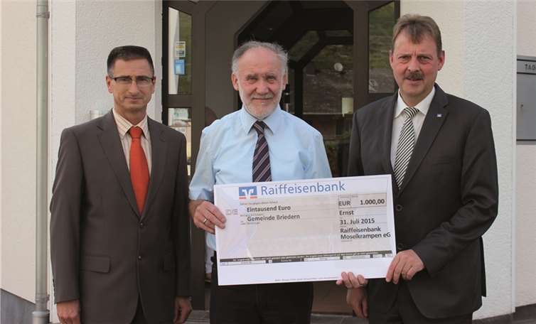 Symbolische Scheckübergabe an Ortsbürgermeister Karl Heinz Bleser durch die Vorstände der Raiffeisenbank Moselkrampen eG. Harald Baltes (l.) und Heinz Blümling (r.).
