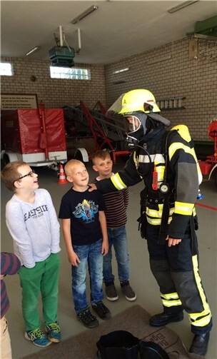 T. Stöver erklärt den Kindern die Ausrüstung der Feuerwehr.