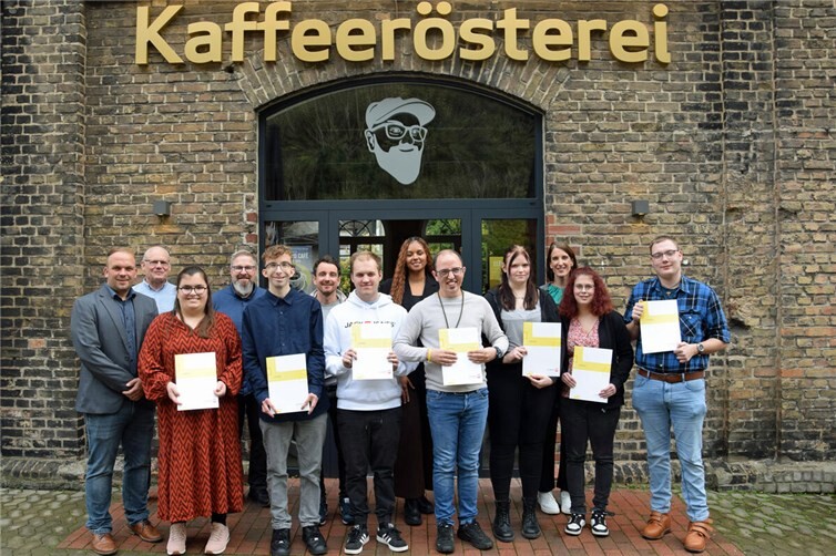 Erfolgreicher Abschluss: Caritas Werkstätten feiern Absolventen Teilnehmende der Berufsbildungsmaßnahme und Mitarbeitende der Caritas Werkstätten vor der Cochemer Kaffeerösterei. Fotos: Tobias Möllney / Caritas Werkstätten