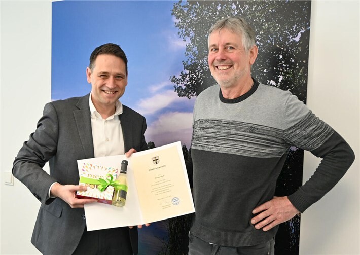 Thomas Hardt (rechts) freut sich über Ehrenurkunde und Präsent, die ihm Bürgermeister Sven Schnieber (links) überreicht.Foto: Stadt Meckenheim
