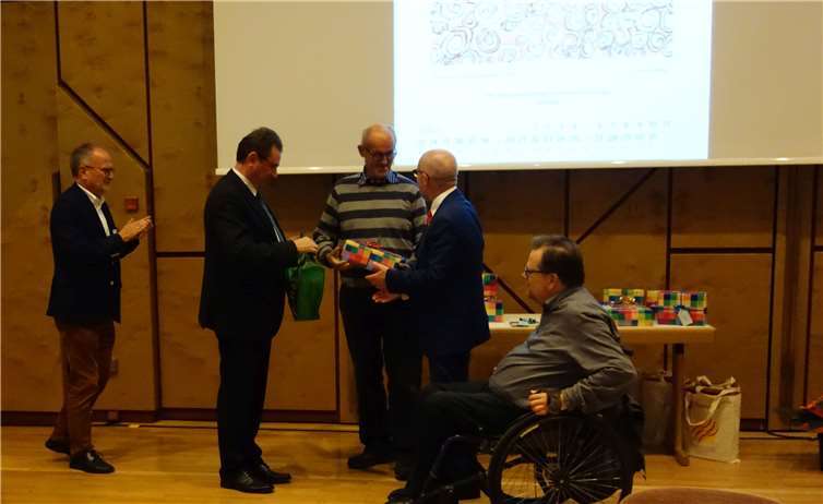 Thomas Kraft wird geehrt für sein Bild „Sommer in Afrika“ und erhält ein Geschenk aus den Händen von Detlef Placzek, Präsident des Landesamtes für Soziales, Jugend und Versorgung RLP.