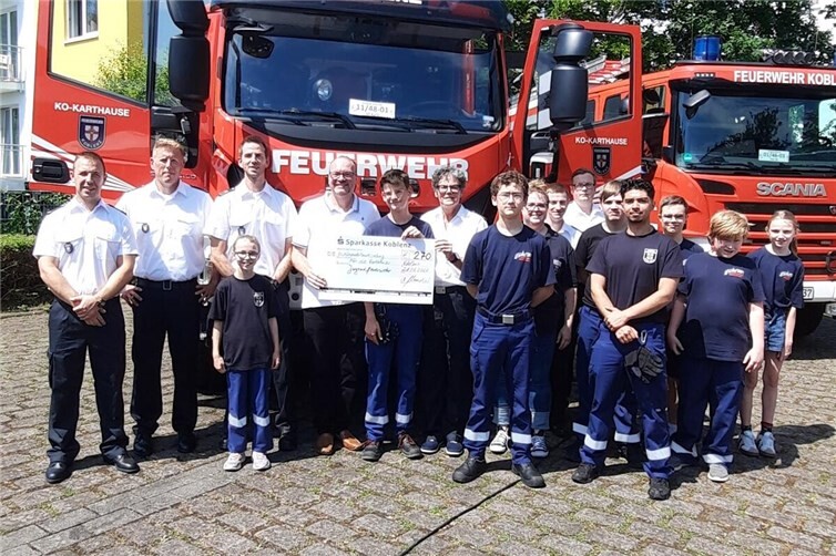 Thorsten Schneider (4. v. l.) übergibt den Spendenscheck des Karthäuser Bürgervereins an die Vorsitzende des Fördervereins der FFW Judith Dill-Quaas (6. v. l.), Jugendwartin Yasmin Christ (8. v. l.) und Einheitsführer Sebastian Alt (3. v. l.)