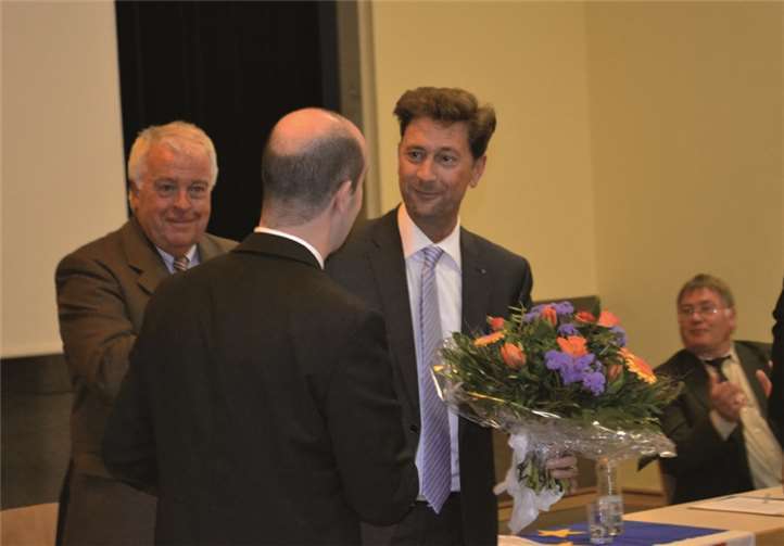 Tino Hackenbruch und Guido Ernst beglückwünschen Detlef Odenkirchen mit einem Blumenstrauß.