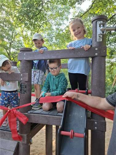 Tobias schneidet das rote Band am neuen Spielgerät durch. 