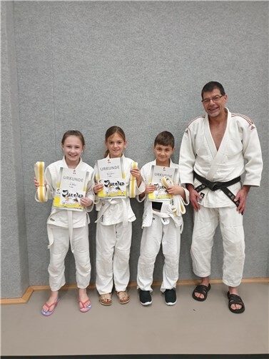 Trainer Jürgen Sabel (re.) konnte nach erfolgreicher Prüfung (v.li.) Nele Ohlberger, Lenya Gansen und Armin Lal Riahi den weiß-gelben Gürtel überreichen.Foto: privat