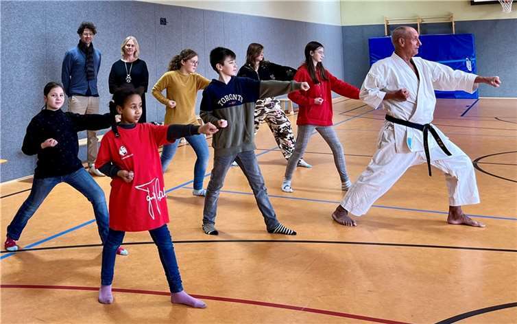 Trainer Klaus Bleser mit seinen Schülerinnen und Schülern der Karate-AG (vorne im Bild) sowie Filialleiterin Anja Pauli von der Sparkasse Kaisersesch mit Pädagogischer Koordinator Christian Theisen von der Kurfürst-Balduin-Schule (hinten im Bild). Quelle: RS+FOS Kaisersesch