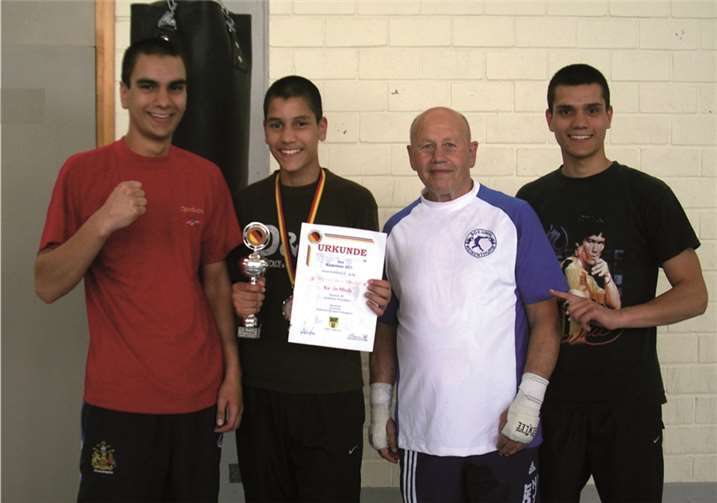 Trainer Ottersbach (3.v.l.) und seine beiden Brüder Robert (1.v.l.) und Marvin (4.v.l.) freuen sich mit Boxchamp Kevin Miah (2.v.l.). privat