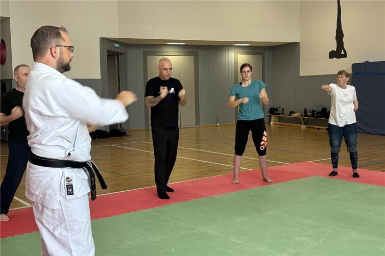 Trainer Peter Büttner (links) zeigt interessierten Einsteigern Karate-Techiken.