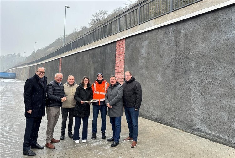 Trotz winterlichem Schneegestöber machten sich Landrat Achim Hallerbach, der 1. Kreisbeigeordnete Phillip Rasbach, der Bürgermeister der Verbandsgemeinde Linz, Frank Becker, und Stadtbürgermeister Helmut Muthers ein Bild vom Ergebnis der Bauarbeiten an der Stützmauer entlang der K 11. Auf den Stand der Dinge ließ sich das Quartett der Verwaltungsspitzen von LBM Bauaufseher Reiner Lahr und Christina Junk vom Kreis-Immobilienmanagement bringen.Foto: Thomas Herschbach