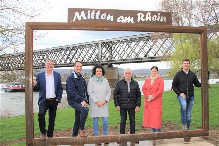 Über den neuen Landschaftsrahmen, den die Verbandsgemeinde Weißenthurm im Rahmen des Kooperationsprojektes „Mitten am Rhein“ am Urmitzer Rheinufer errichtet hat, freuen sich (v.li.) Ortsbürgermeister Norbert Bahl, der Bürgermeister der Verbandsgemeinde Weißenthurm, Thomas Przybylla, die Erste Beigeordnete der Ortsgemeinde Urmitz, Marion Höfer, der Beigeordnete Johannes Weiler, Projektmanagerin Alessa Strubel und der Urmitzer Beigeordnete Oliver Koch. Foto: VG Weißenthurm / Katharina Demleitner