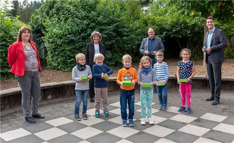 Über die Frühstücksdosen von Innogy Westenergie freuen sich gemeinsam mit den Erstklässlern die Kommunalbetreuer Fabian Vocktmann (links) und Beate Ziegler, Bürgermeister Guido Nisius (2. von rechts) und Schulleiterin Angelika Schifferings (links). Foto: innogy Westenergie
