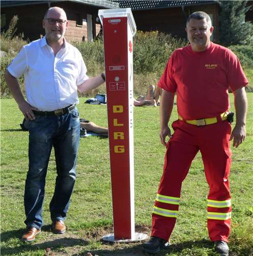 Übergabe der Notrufsäule von der DLRG an die Gemeinde Rieden: Bürgermeister Andreas Doll und Michael Seimetz, Stellvertretender Leiter Einsatz DLRG Landesverband Rheinland-Pfalz. Foto: privat