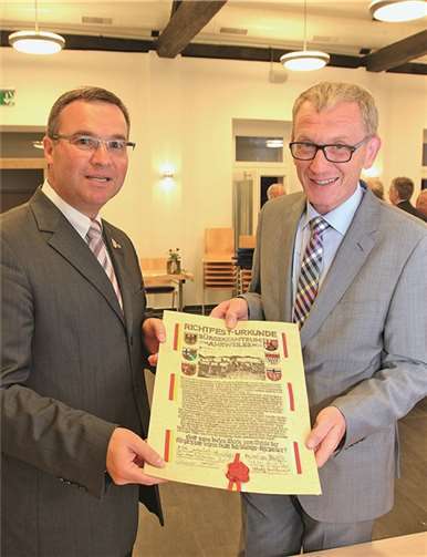 Überraschendes Geschenk: Die originale, kunstvolle und gesiegelte Urkunde vom Richtfest des Bürgerzentrums am 12. Mai 1999, präsentiert von Horst Gies (links) und Guido Orthen.