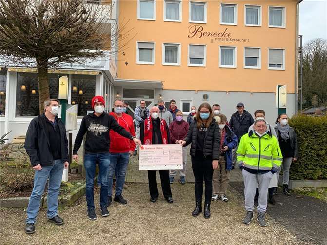 Ulrich van Bebber (Mitte, mit Schal) freut sich im Namen der Lebenshilfe über die Spende, die Werner Homburger (3. von links) mit seinem Fanclub den Bewohnerinnen und Bewohner vor ihrem neuen Domizil in Remagen Rolandseck überbrachte. Foto: Lebenshilfe