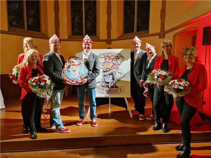 Umrahmt vom ehefraulichen „Jemös“: Norbert Adams (4. v.L.) hält mit Adjutant Ralf Rondi das Nädelchen-Bild, Adjutanten Horst Schreiber und Michael Nietzard (v.L.) stehen rechts neben dem Karnevalsordenplakat. Fotos: AWi