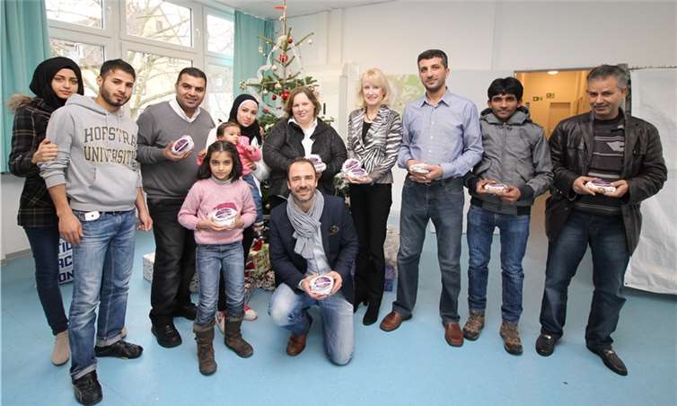 Unter anderem im Rauental übergaben Sabine Pauly (5. v.r.) und Frederik Wenz (vorne) gemeinsam mit Bürgermeisterin Marie-Theres Hammes-Rosenstein (4. v.r.) Weihnachtsstollen, gespendet von der Sabine Pauly GmbH, an Bewohner der dortigen Flüchtlingsunterkunft. Stadt Koblenz