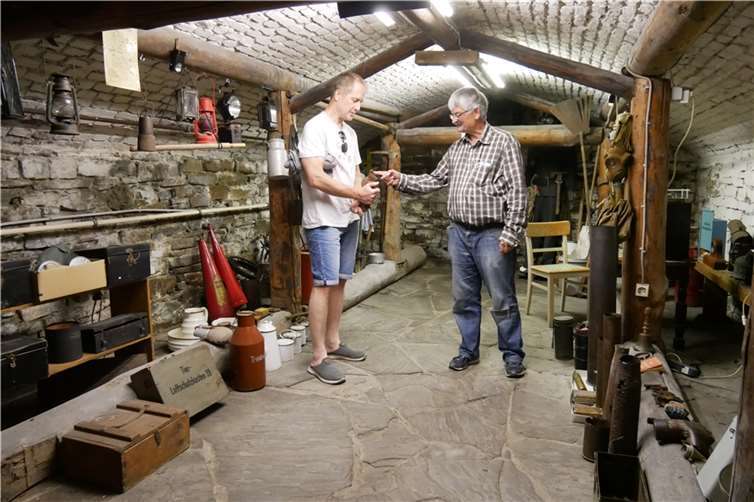 Unter dem 1885 errichteten Rathaus in Unkel befindet sich ein Luftschutzkeller, der 1936 eingerichtet wurde und während des Fliegeralarms im II. Weltkrieg bis zu 40 Personen Schutz bot. Hier lässt Wolfgang Rosen (rechts) interessierte Besucher fühlen, wie schwer ein großer Bombensplitter sein kann.  Foto: CD