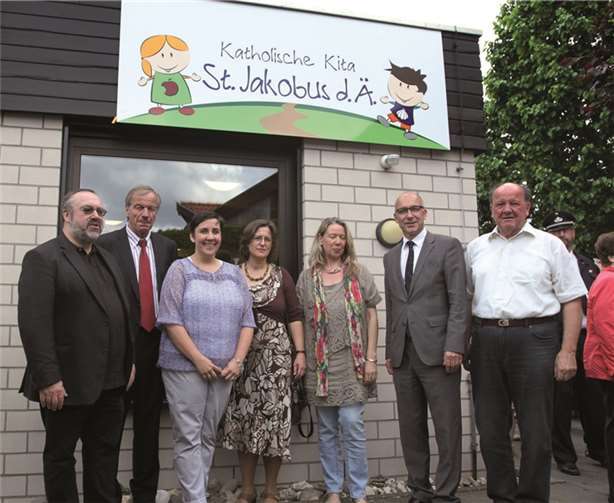 Unter dem neuen Logo (v.li.): Pfarrvikar Franz-Josef Steffl, Ortsvorsteher Ferdi Koll, Leiterin Rabea Becker, Pastoralreferentin Ursula Bruchhausen, Kirchenvorstandsmitglied Anne Schnurpfeil, Bürgermeister Bert Spilles, Ortsvorsteher (jetzt ehemaliger) Hermann-Josef Nöthen.