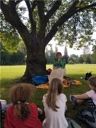 Unter einem uralten Kirschbaum erzählte die Märchenerzählerin Griseldis den Kindern spannende Geschichten.  Foto: Christiane Guth