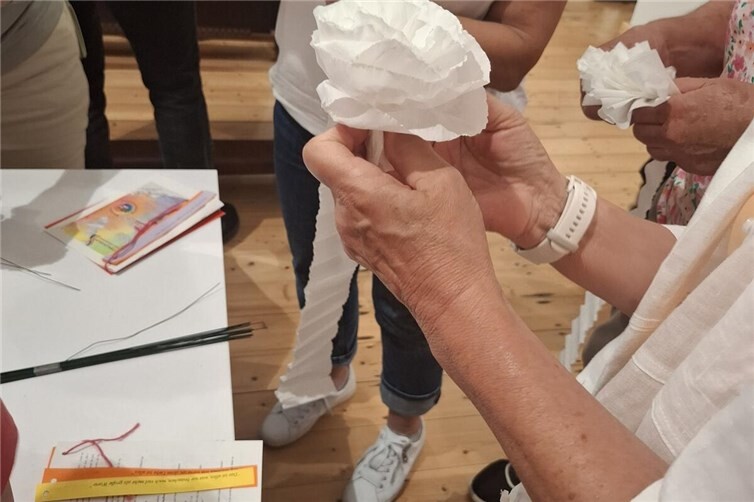 Untermalt von einer Erzählung werden an einer Station Krepppapierrosen gebastelt