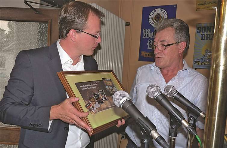 VG-Bürgermeister Jörg Lempertz überreichte dem Mendiger Autor als Geste der Anerkennung eine Collage mit Fotos von Astors Buchtiteln vor dem Hintergrund der Mendiger Felsenkeller.