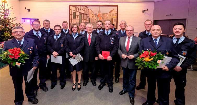 Verbandsgemeindebeigeordneter Heinz Schmitz und Ortsbürgermeister Markus Fischer im Kreis der ernannten und beförderten Wehrleute.  DL