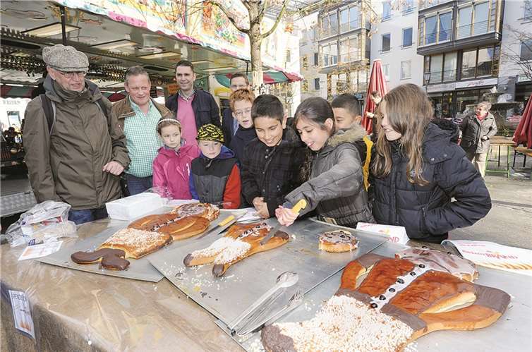Viertklässler schnitten im Beisein von Volker Danko von der Werbegemeinschaft Bad Neuenahr (3.v.li.) und anderen, schon bald resolut an beiden Enden des Weckmanns in Bad Neuenahr.FIX