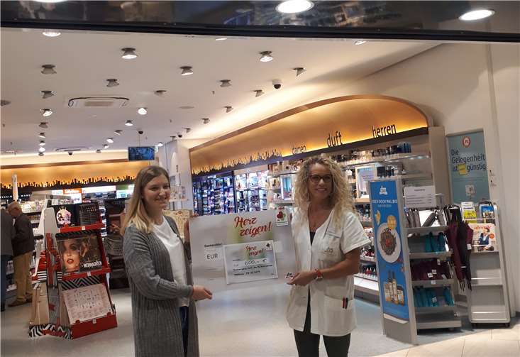 (V.l.) Mareike Blum, Mitarbeiterin der Interkulturellen Dienste, Asyl- und Flüchtlingsberatung, nimmt den symbolischen Scheck aus den Händen von Hannelore Schaden, Filialleiterin der dm-Löhr Center Filiale, entgegen.